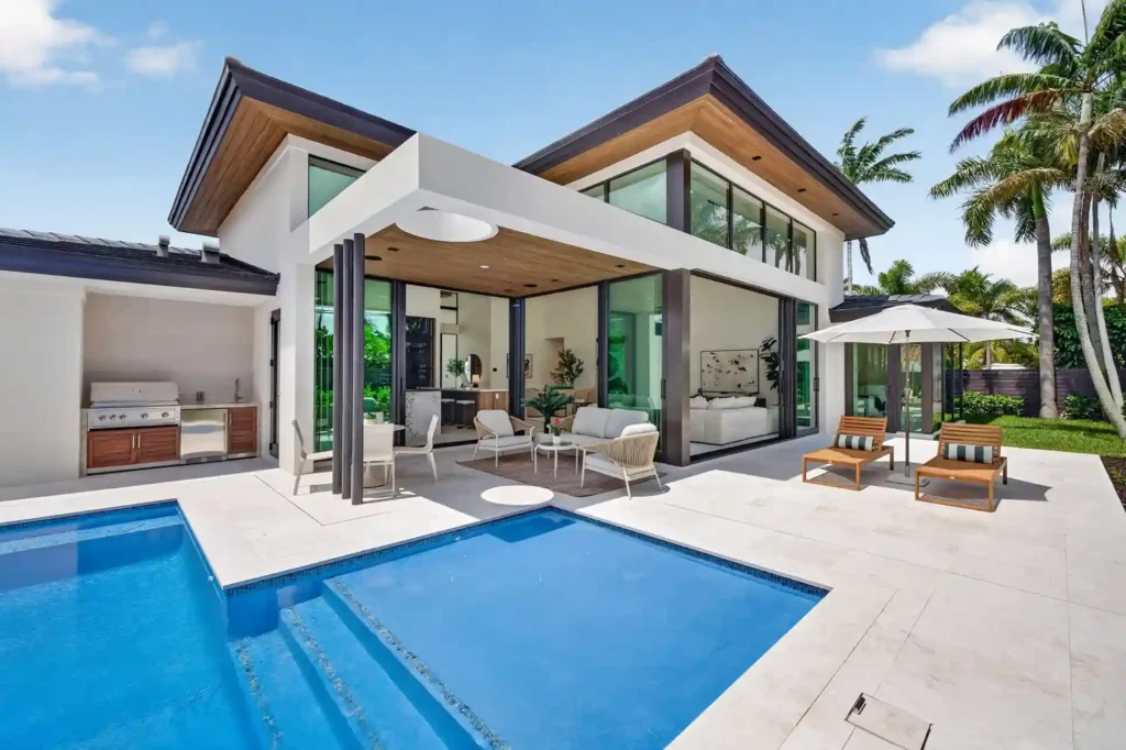 Modern luxury home exterior featuring covered patio, outdoor seating, and contemporary architecture.