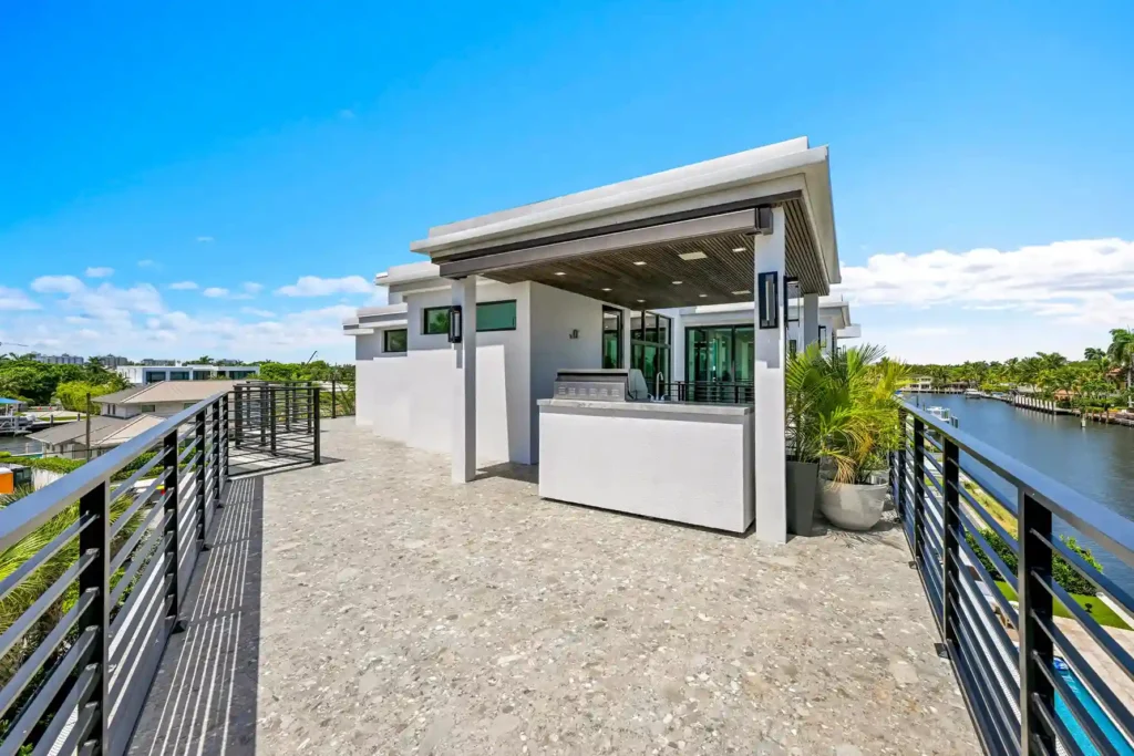 Modern waterfront home exterior with clean architectural lines and tropical landscaping.