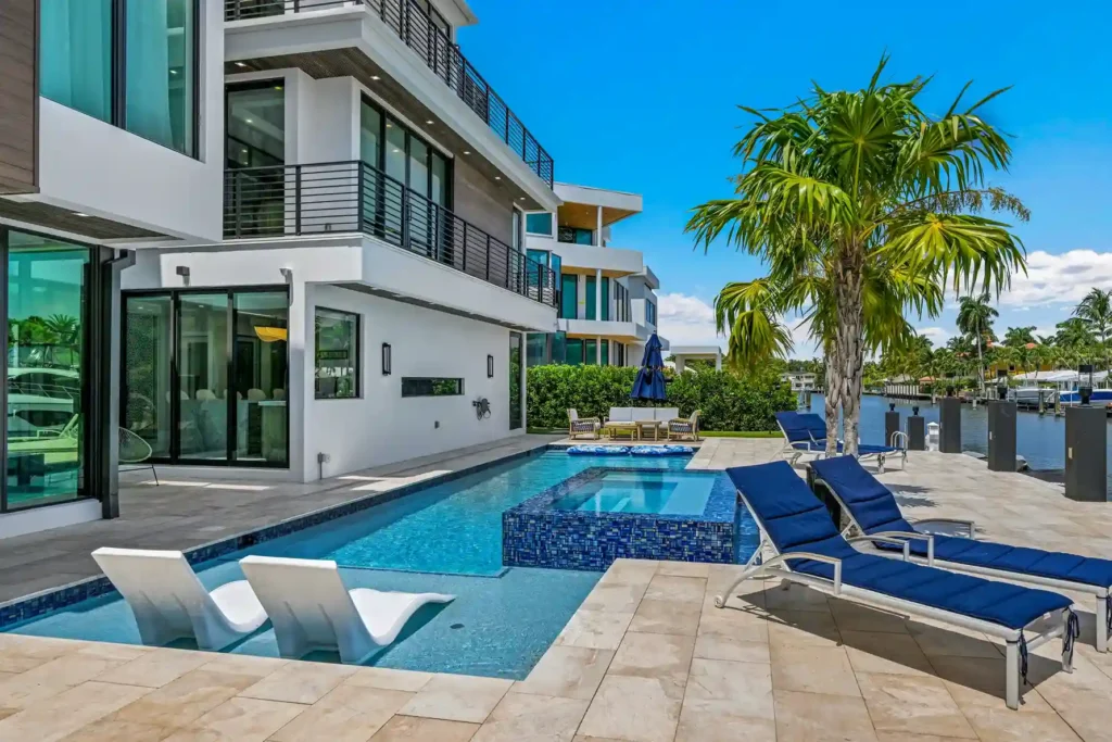Luxury waterfront home with expansive windows, swimming pool, and contemporary exterior.