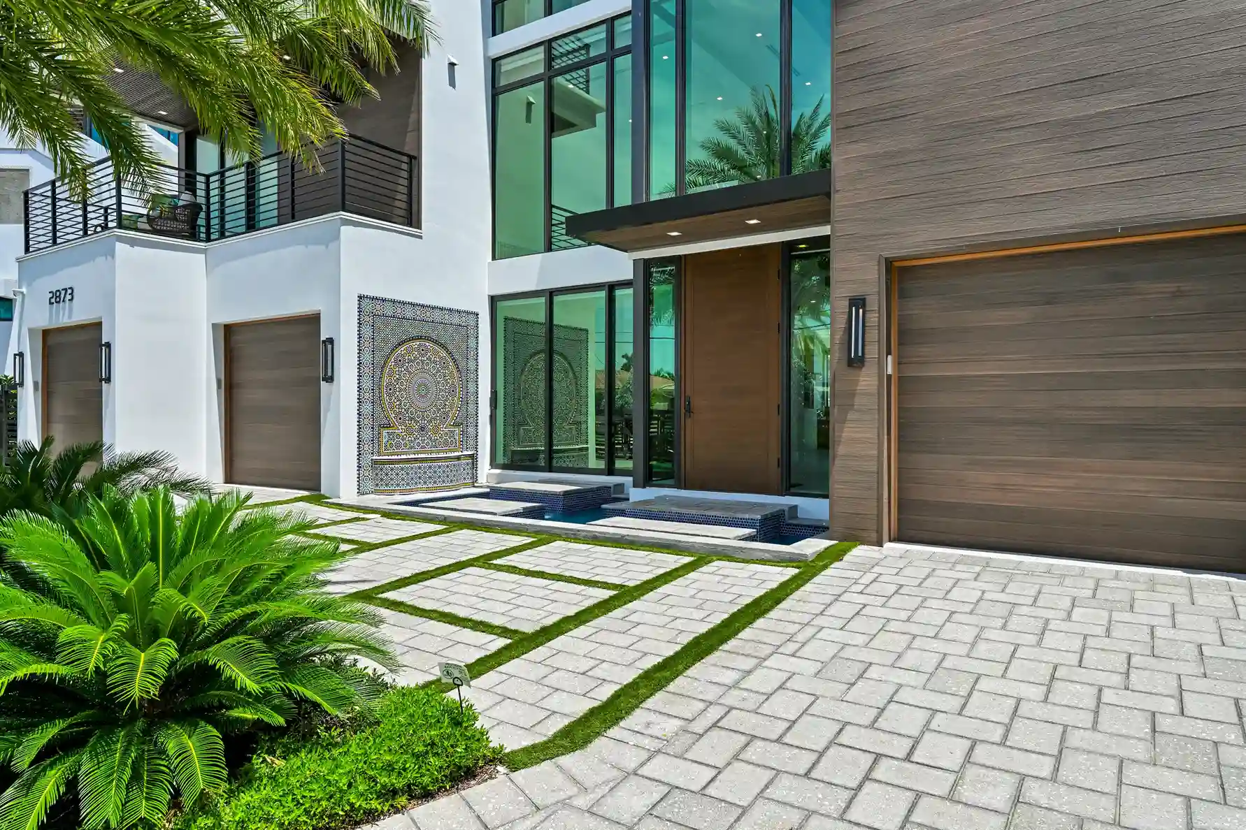 Modern front entry featuring oversized glass windows, wood paneling, and landscaped walkway.