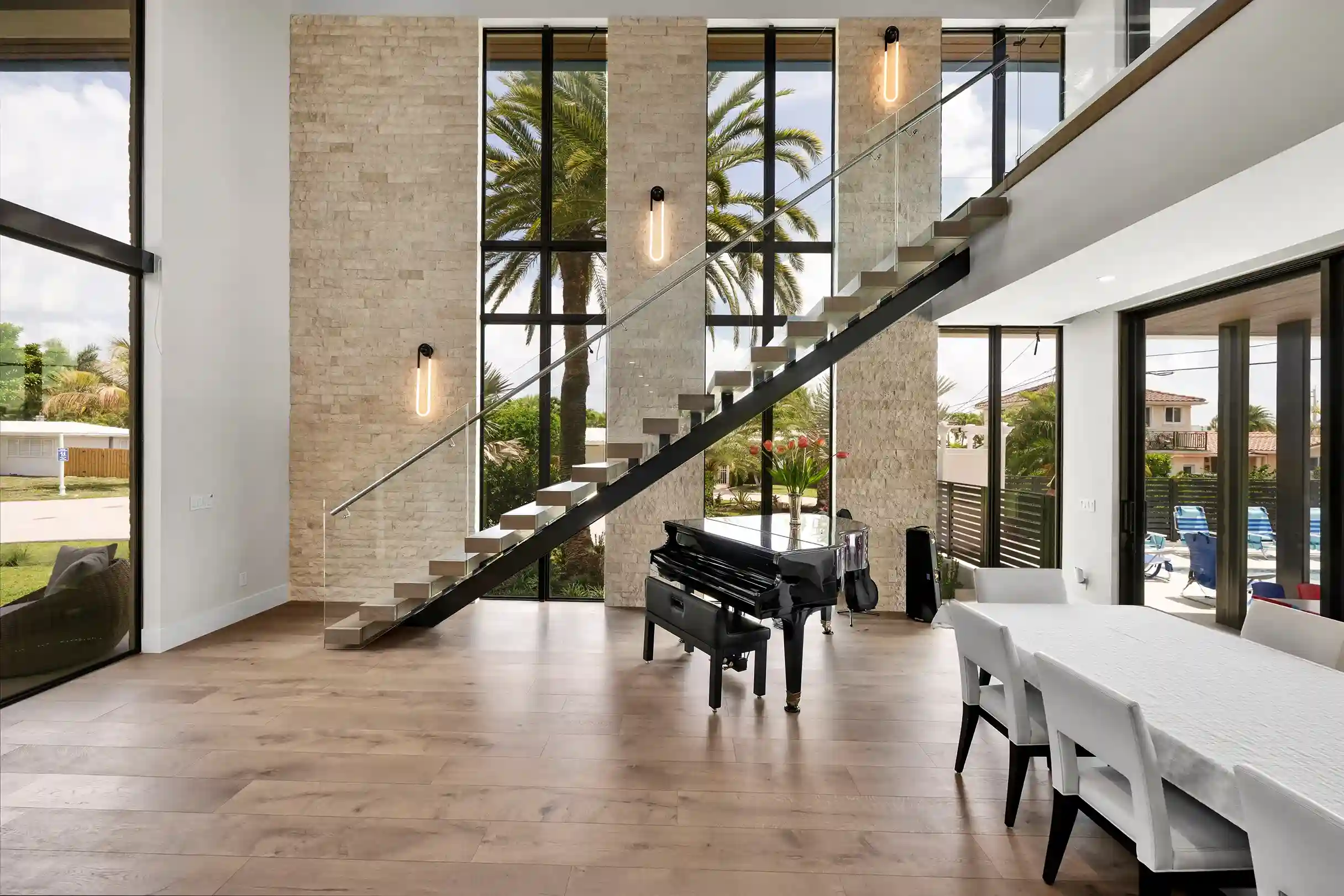 Grand modern entryway with floating staircase, glass walls, and double-height foyer.