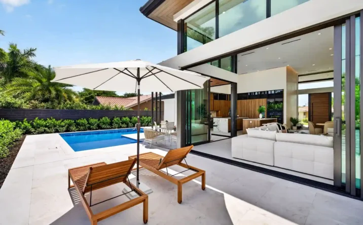 Covered outdoor living space overlooking a luxury swimming pool and landscaped backyard.