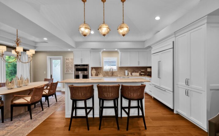 Open kitchen with island seating and pendant lighting by CKA Construction