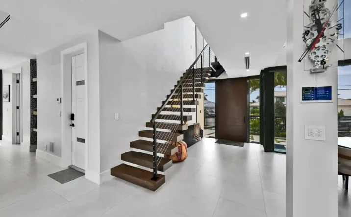 Modern floating staircase with glass accents and open-concept foyer design.