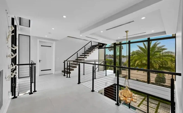Grand foyer with floating staircase, floor-to-ceiling windows, and contemporary architectural details.