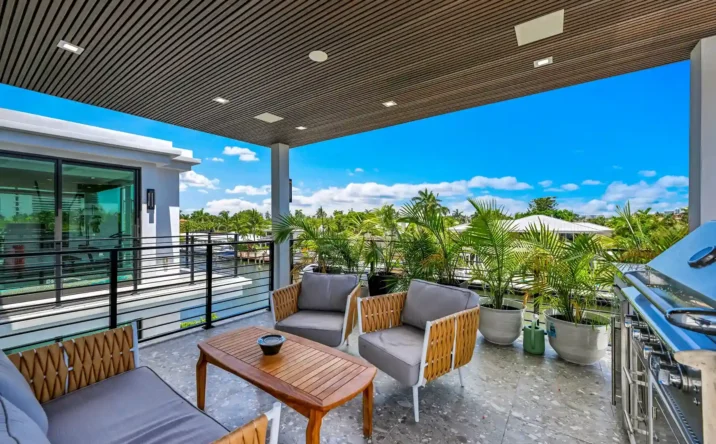 Covered outdoor patio with wood ceiling overlooking a private waterfront and tropical landscaping.