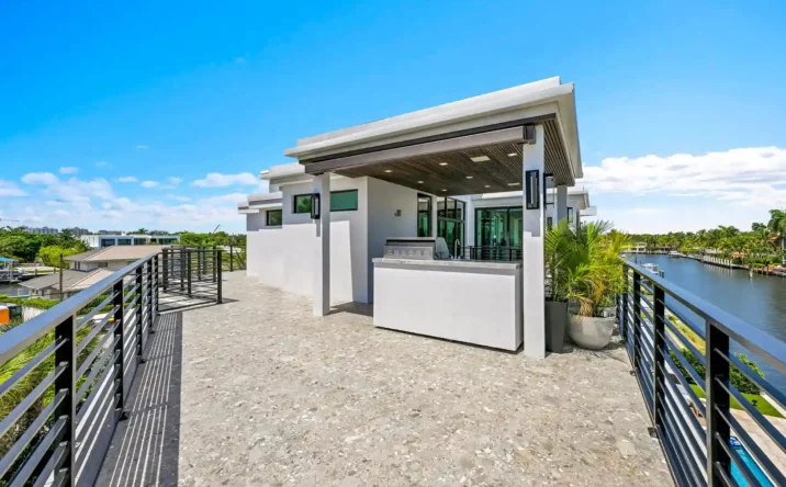 Modern waterfront home exterior with clean architectural lines and tropical landscaping.