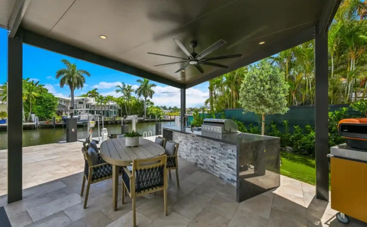 Spacious covered outdoor living area with ceiling fan and landscaped backyard views.