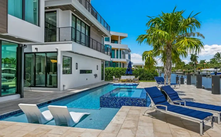 Luxury waterfront home with expansive windows, swimming pool, and contemporary exterior.