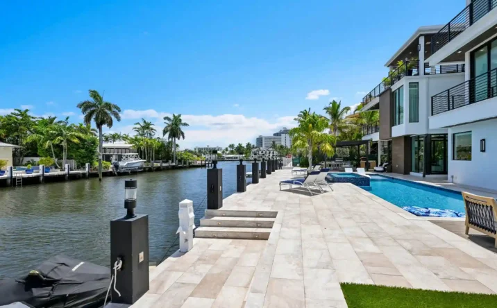 Modern waterfront backyard with swimming pool, spacious patio, and canal views.