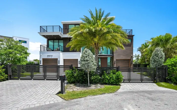 Front exterior of a modern luxury home with tropical landscaping and contemporary architectural design.