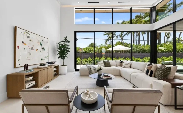 Spacious modern living room with oversized windows overlooking lush outdoor landscaping.