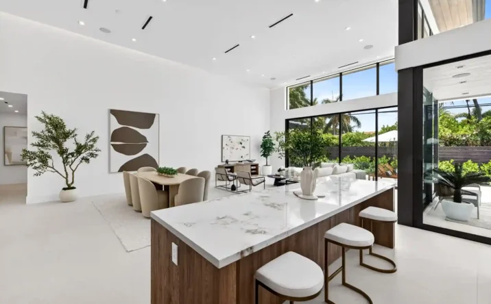 Bright modern living room with floor-to-ceiling windows, white furnishings, and contemporary artwork.