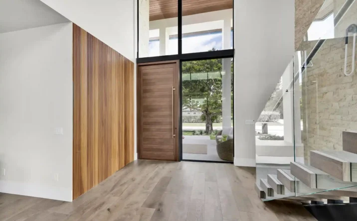 Contemporary entryway featuring a pivot front door, wood paneling, and minimalist design.