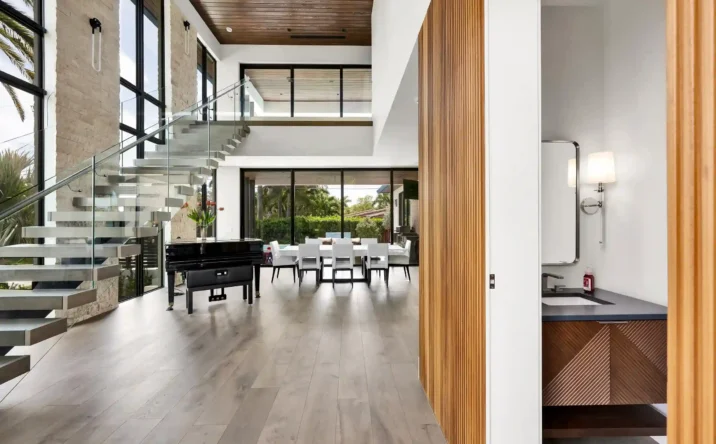 Grand modern foyer with floating staircase, wood accents, and floor-to-ceiling glass walls.